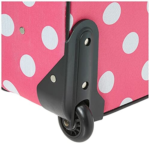 Close-up of a pink suitcase with white polka dots and a black wheel.